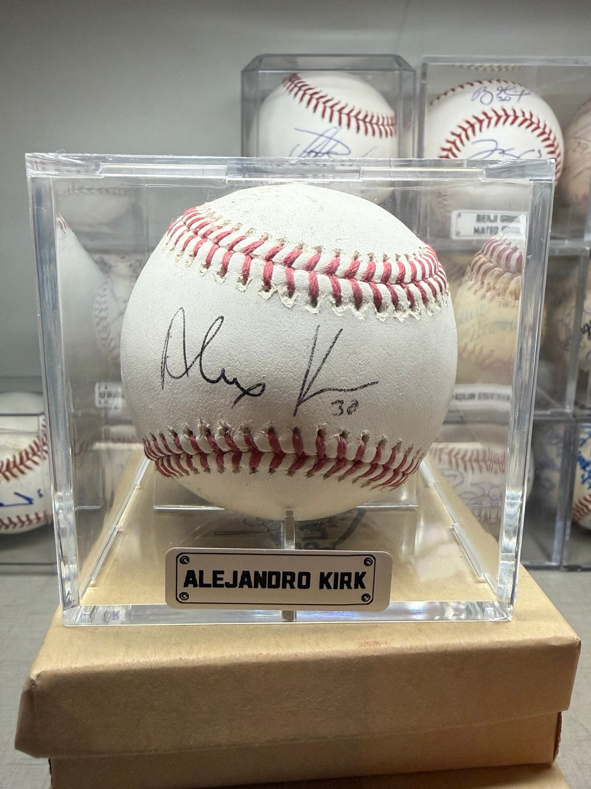 Pelota autografiada por Alejandro Kirk en exhibidor - vista frontal